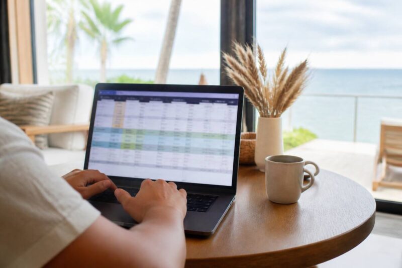 Iemand vergelijkt vakanties op een laptop met een rustige werkplek bij daglicht